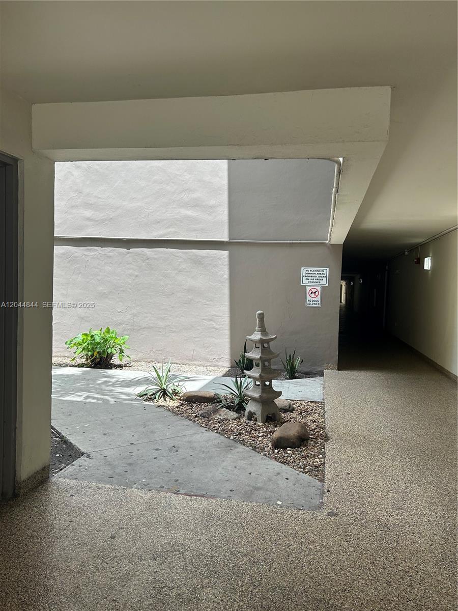 A stone pagoda stands in a small landscaped courtyard between two building corridors — MIAMI, FL
