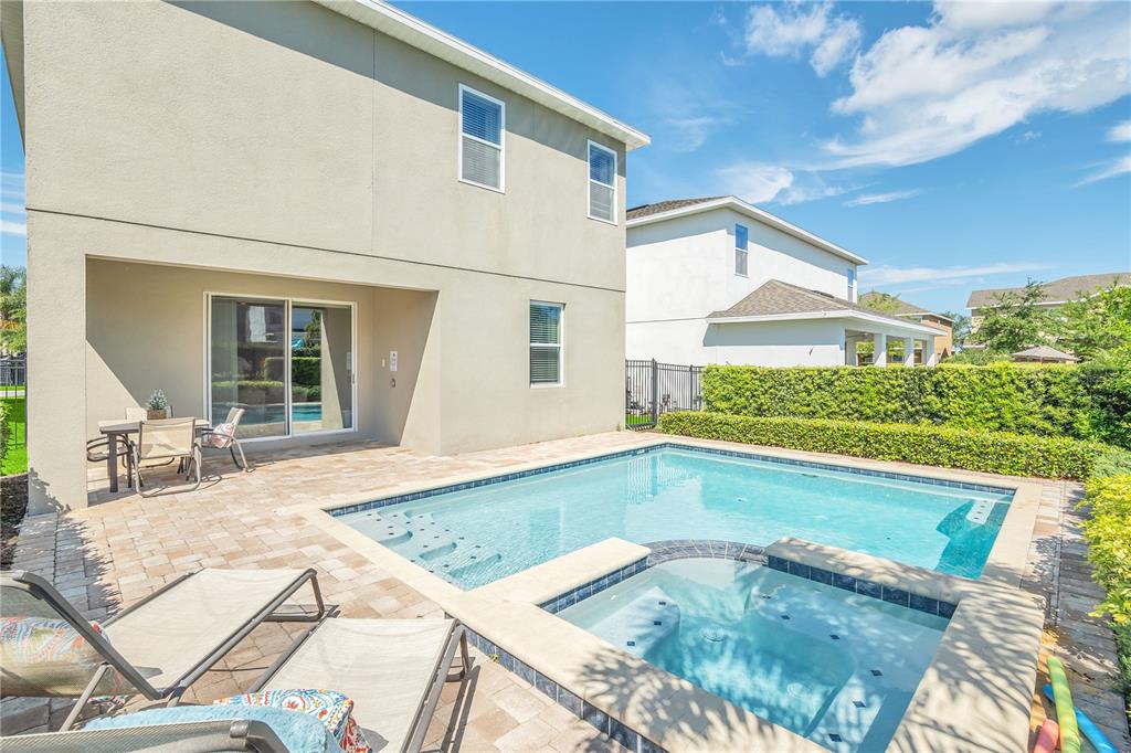 A two-story house exterior features a backyard patio, a swimming pool, and a hot tub — 801 LASSO DRIVE, KISSIMMEE, FL