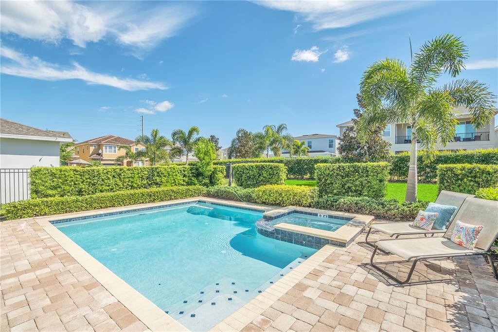 A backyard swimming pool and hot tub with lounge chairs on a paved patio — 801 LASSO DRIVE, KISSIMMEE, FL