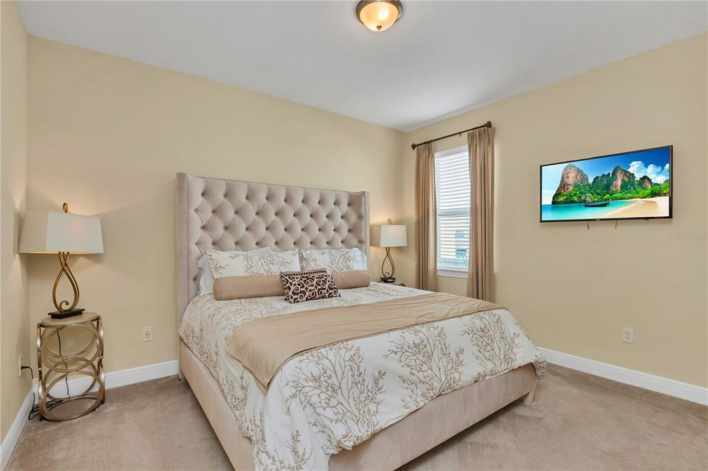 A bedroom features a tufted headboard, a patterned bedspread, two bedside lamps, and a wall-mounted television — 801 LASSO DRIVE, KISSIMMEE, FL