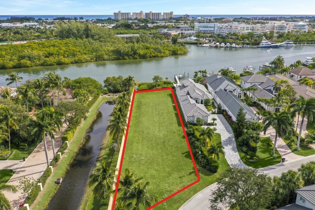 An aerial view shows a vacant, rectangular waterfront lot outlined in red next to houses — 0 Fishermans Way, Jupiter FL 33477, JUPITER, FL