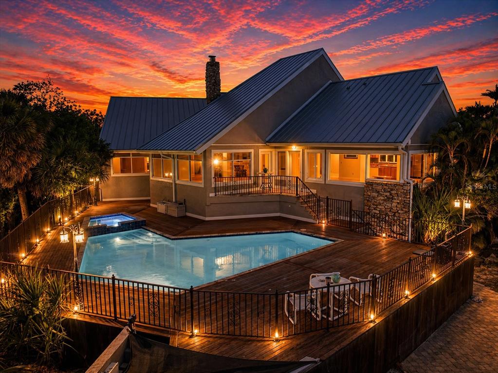 A house with a metal roof, stone chimney, and a wooden deck featuring a swimming pool — 4024 CASEY KEY ROAD, NOKOMIS, FL