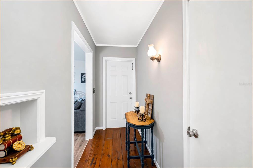 A hallway with hardwood floors, a small console table, and a wall-mounted light fixture — 715 AVENUE B SW, WINTER HAVEN, FL