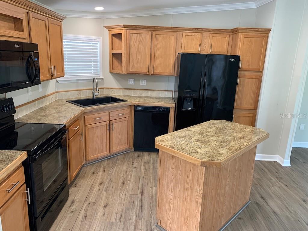 A kitchen features oak cabinets, black appliances, a corner sink, and a small center island — 6632 JACK STREET, PUNTA GORDA, FL