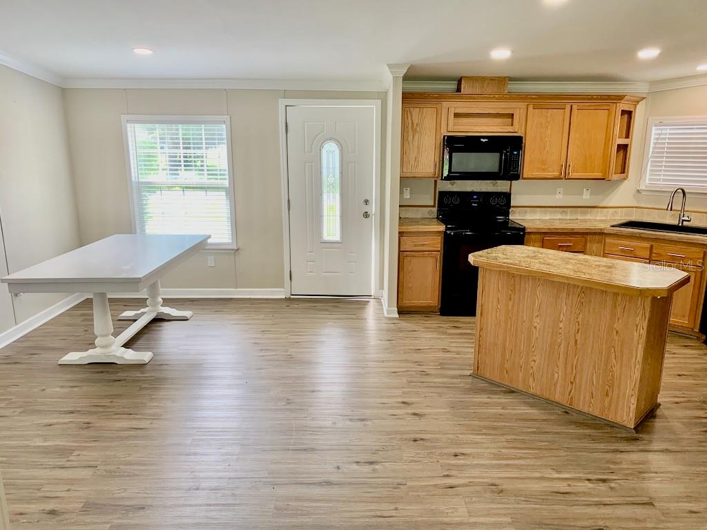A kitchen and dining area with light wood-look flooring, oak cabinets, and a white table — 6632 JACK STREET, PUNTA GORDA, FL