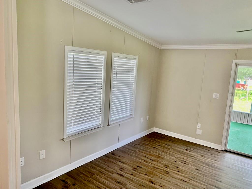 An empty room with light-colored walls, two windows with blinds, and wood-look flooring — 6632 JACK STREET, PUNTA GORDA, FL