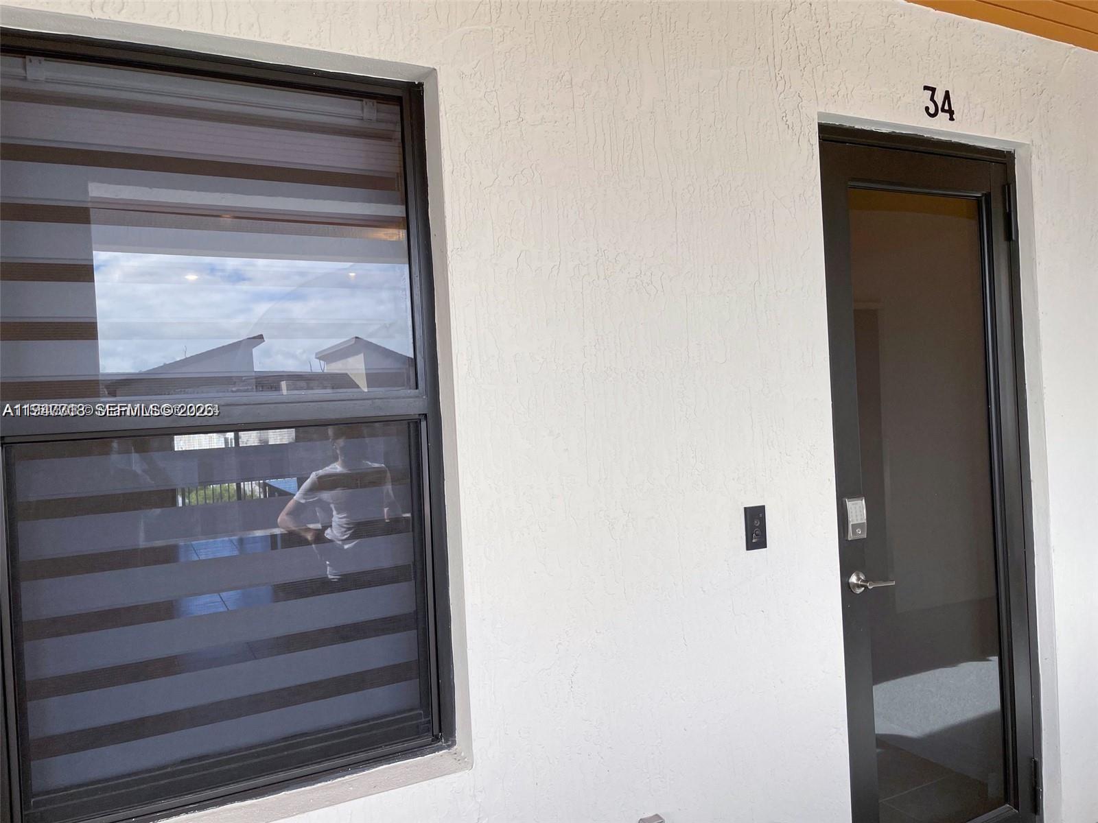 A window with horizontal blinds sits next to a glass-paneled door labeled number 34 — 8151 NW 104th Ave # 34, Doral FL 33178, DORAL, FL