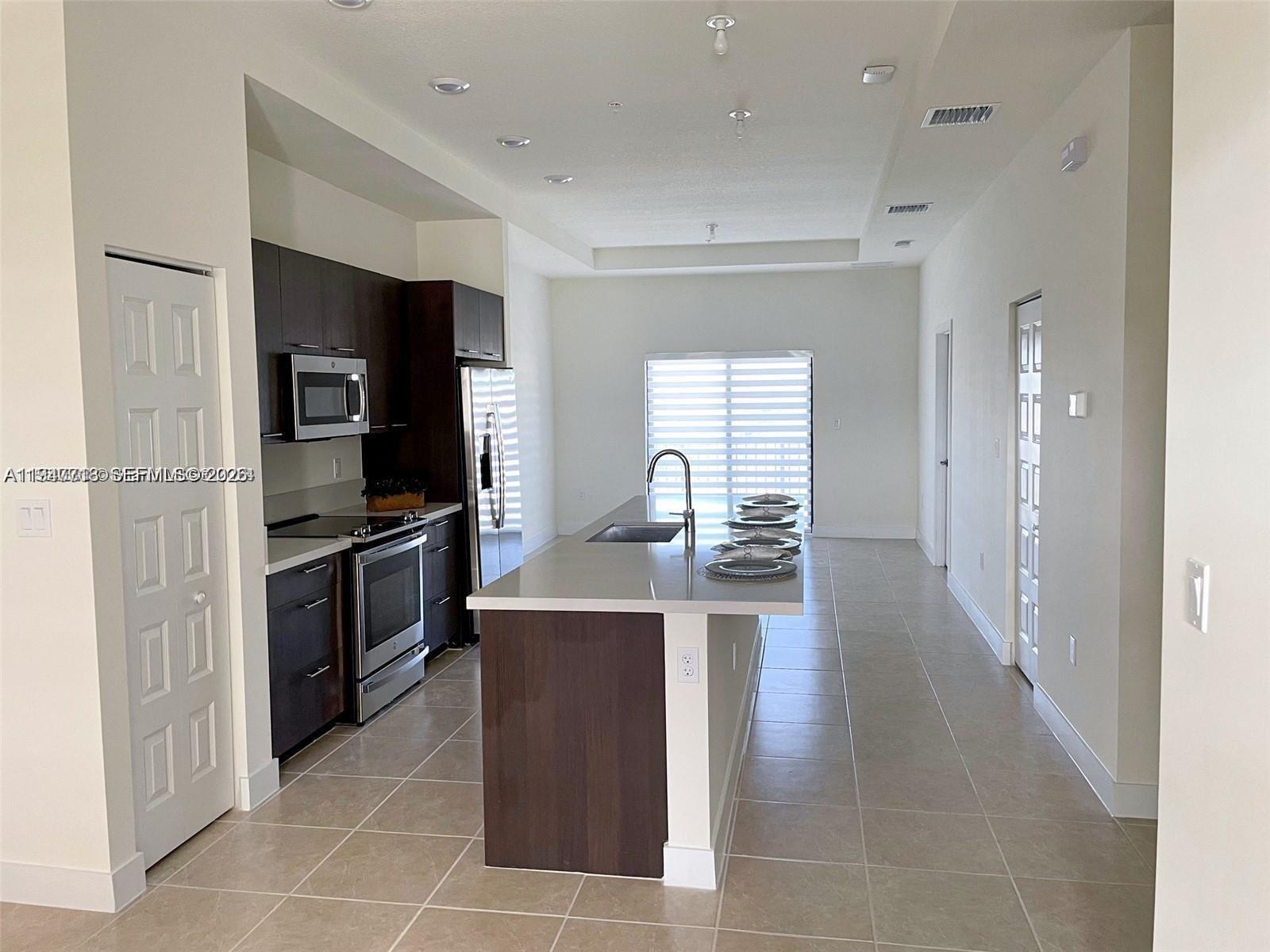 A modern kitchen features dark wood cabinetry, stainless steel appliances, and a central island — 8151 NW 104th Ave # 34, Doral FL 33178, DORAL, FL