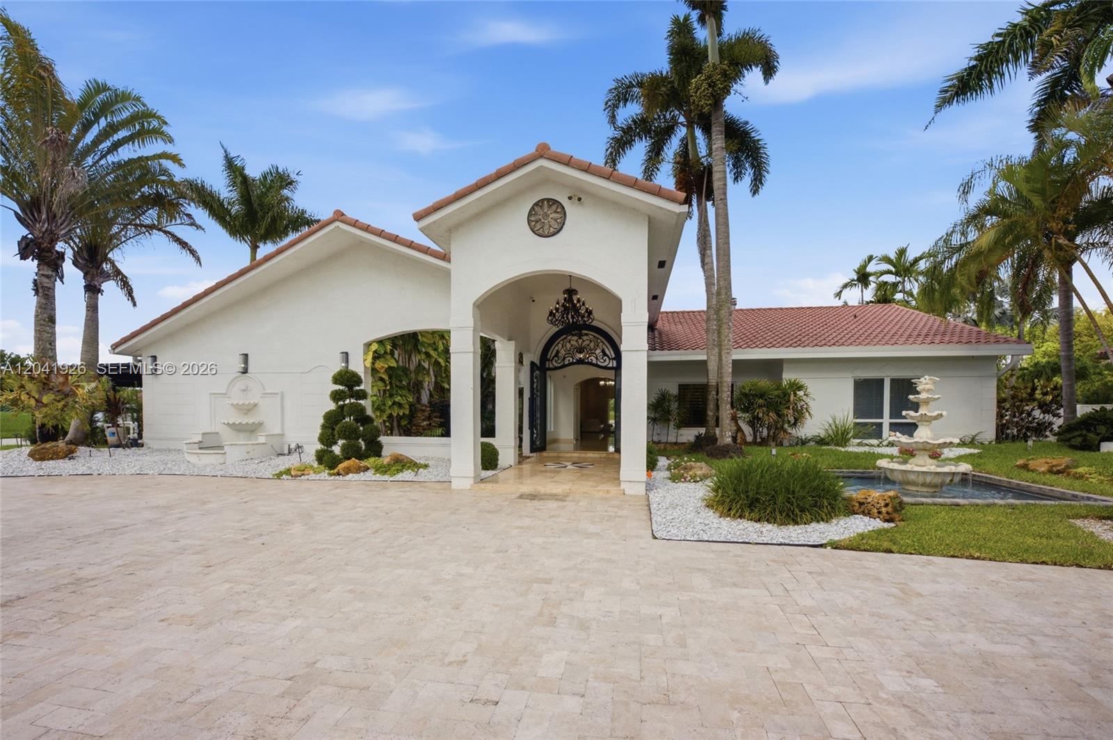 A white house with a tiled roof, arched entryway, and two fountains in the front yard — 16170 Saddle Ln, Weston FL 33326, WESTON, FL
