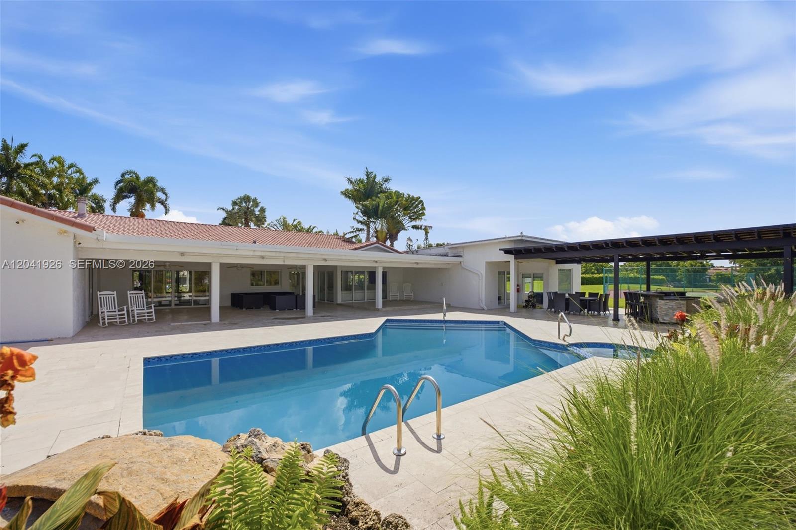 A swimming pool sits on a patio in front of a house with a pergola — 16170 Saddle Ln, Weston FL 33326, WESTON, FL