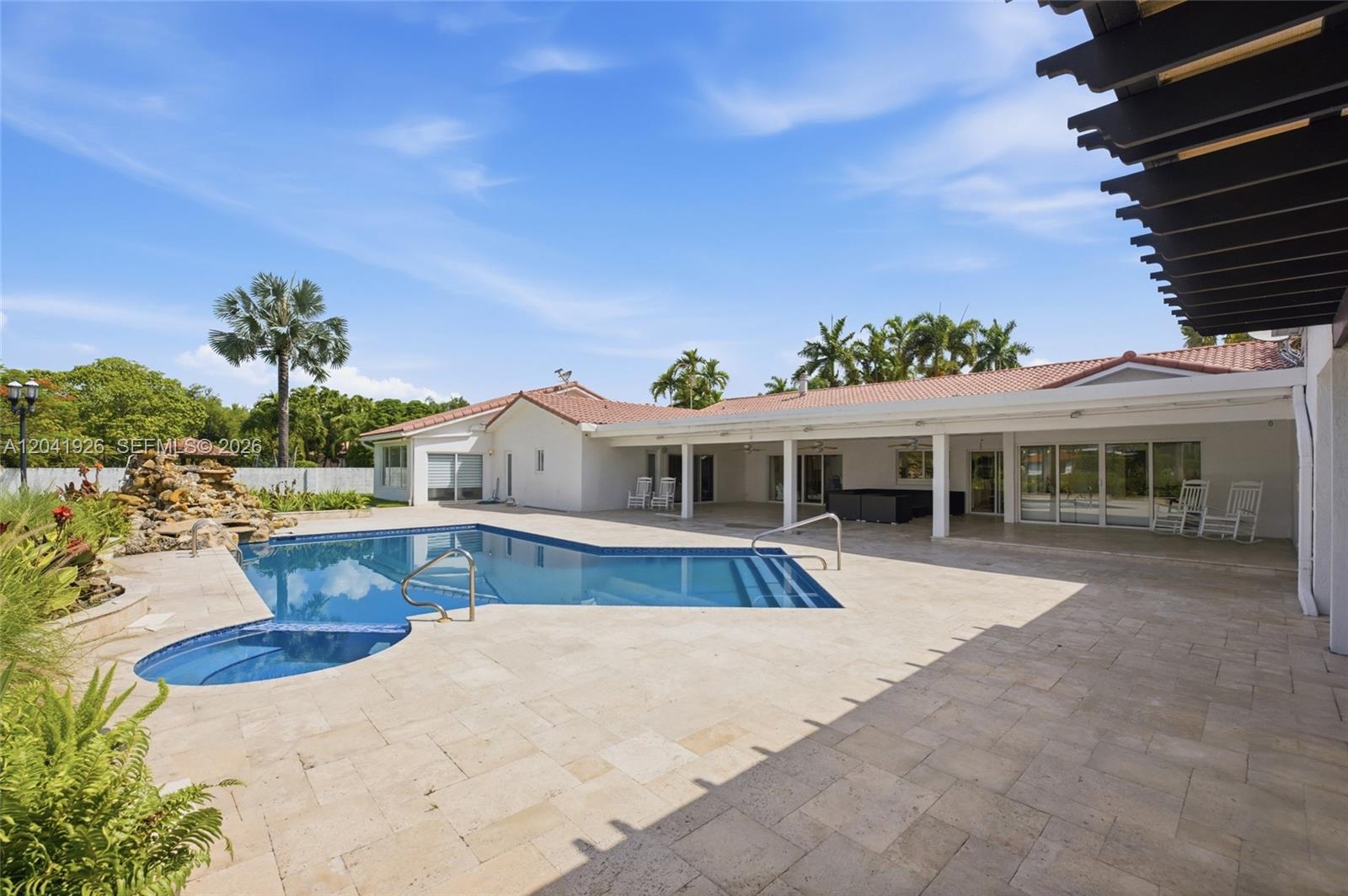 A backyard features a swimming pool with a spa, stone patio, and covered porch — 16170 Saddle Ln, Weston FL 33326, WESTON, FL