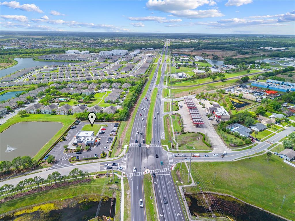 This aerial view shows a commercial building with a parking lot near a highway intersection — 1591 JOHN YOUNG PKWY, KISSIMMEE, FL