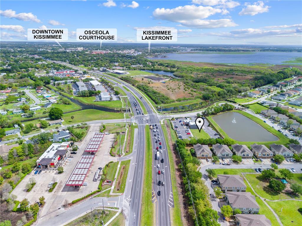 This aerial view shows a commercial property location near a highway, lake, and residential area — 1591 JOHN YOUNG PKWY, KISSIMMEE, FL