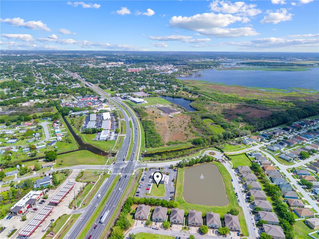 This aerial view shows a commercial lot with a pond and nearby residential housing — 1591 JOHN YOUNG PKWY, KISSIMMEE, FL