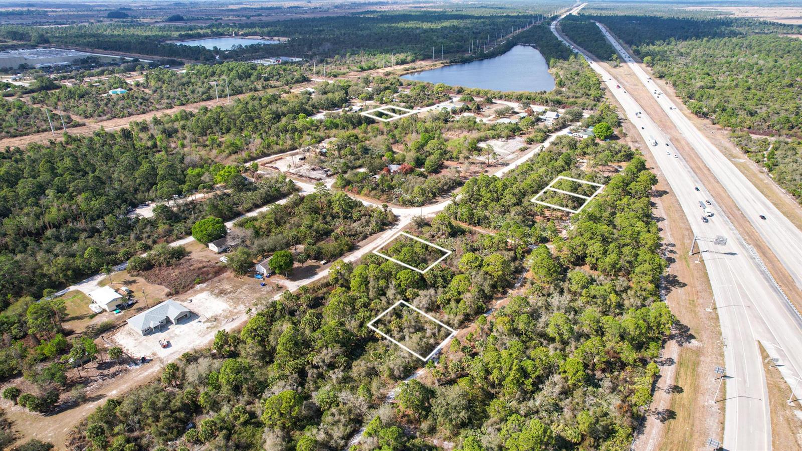 An aerial view shows several wooded lots outlined in white near a highway and lake — 2145 94th Avenue, Vero Beach FL 32966, VERO BEACH, FL