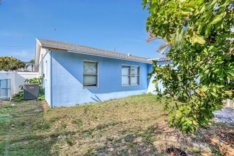 The exterior of a light blue house features two windows and a central air conditioning unit — 3308 Lake Avenue, West Palm Beach FL 33405, WEST PALM BEACH, FL