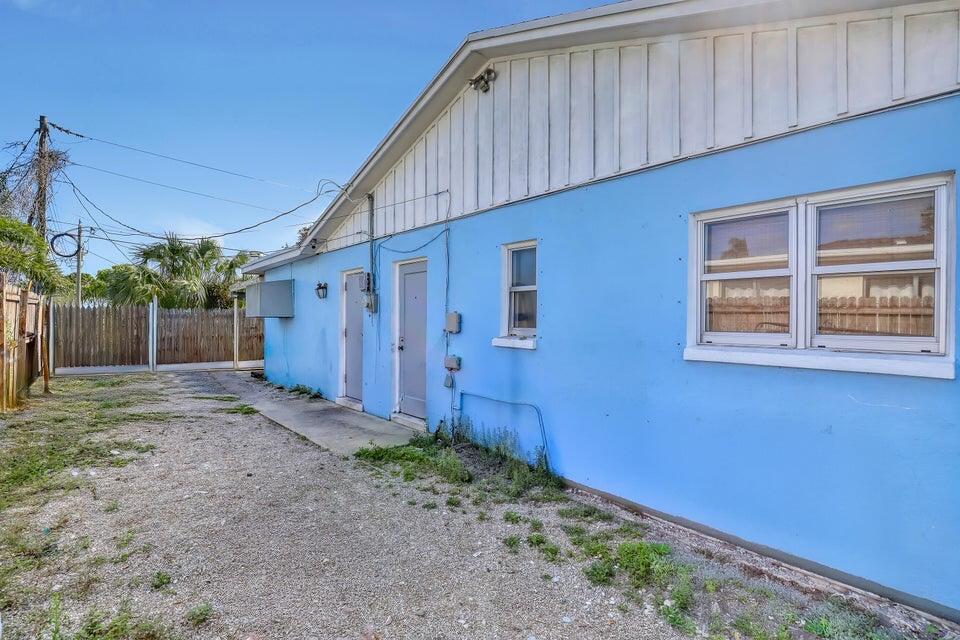 The exterior of a blue house features a gravel yard, two doors, and two windows — 3308 Lake Avenue, West Palm Beach FL 33405, WEST PALM BEACH, FL