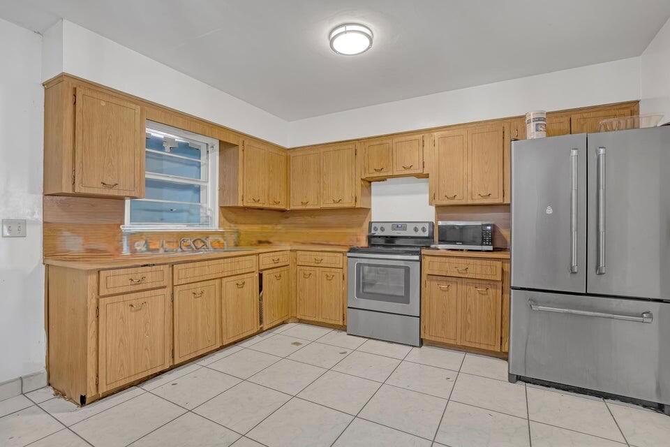 A kitchen with wood cabinets, stainless steel appliances, and white tile flooring — 3308 Lake Avenue, West Palm Beach FL 33405, WEST PALM BEACH, FL