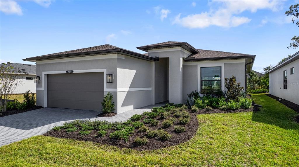 A single-story house with a gray stucco exterior, a two-car garage, and landscaped front yard — 14363 HAMMOCK OAK STREET, PARRISH, FL