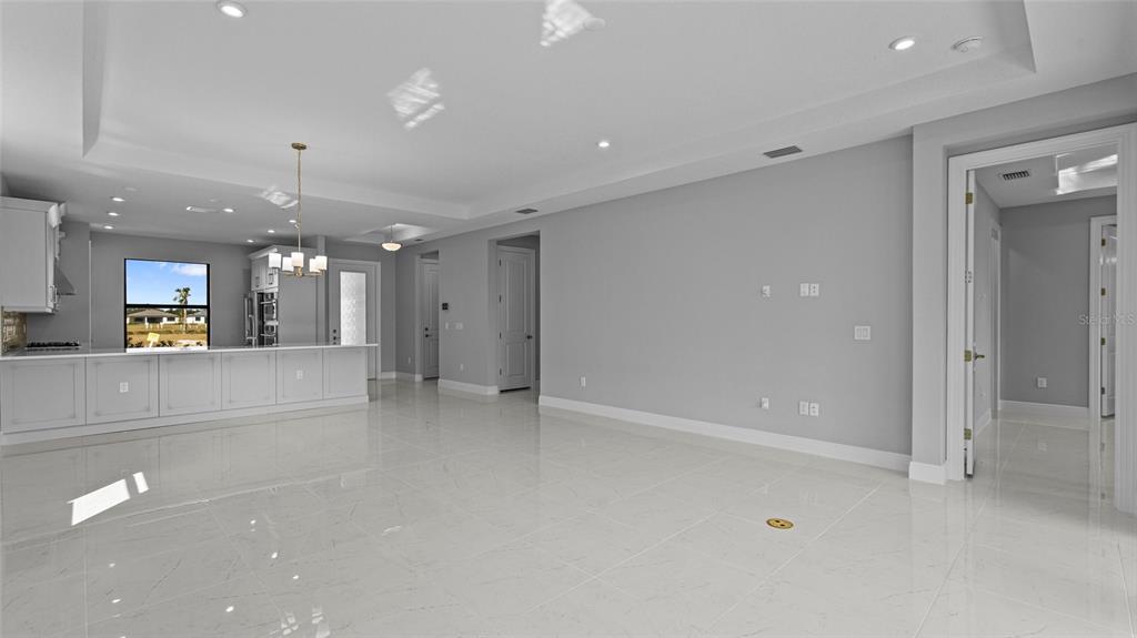 A spacious, modern living area features white tile floors, light gray walls, and a kitchen island — 14363 HAMMOCK OAK STREET, PARRISH, FL