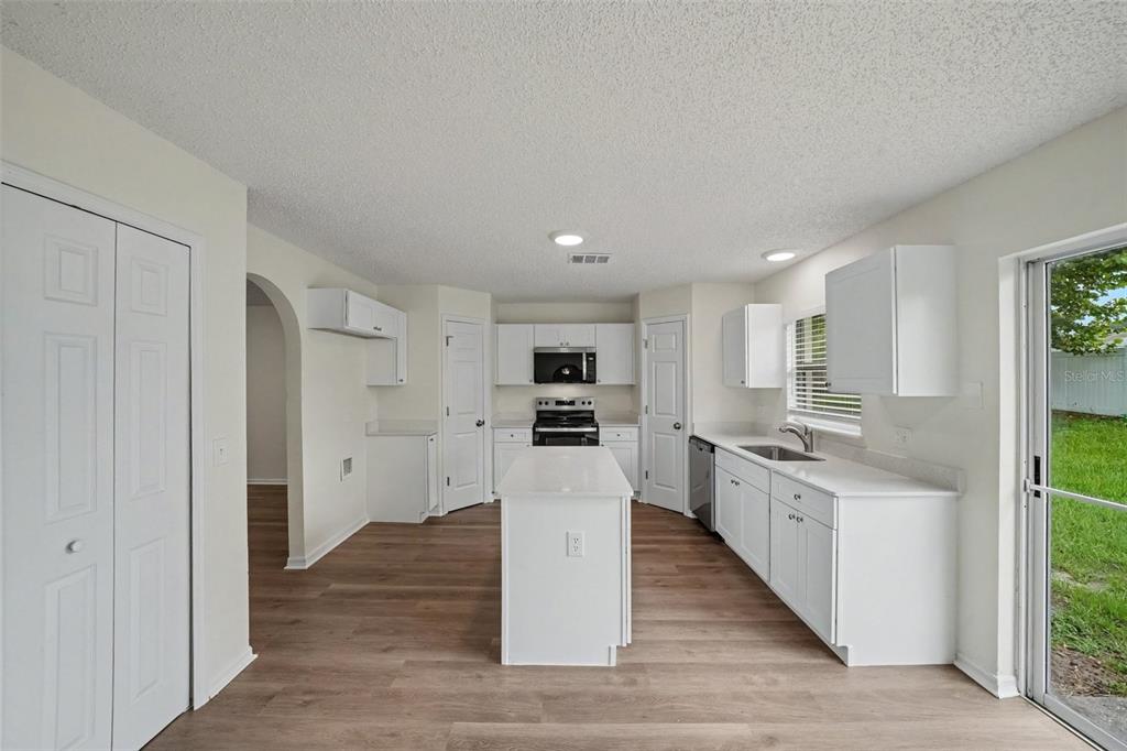 A kitchen with white cabinets, a central island, and wood-look flooring — 1099 WELCH HILL CIRCLE, APOPKA, FL