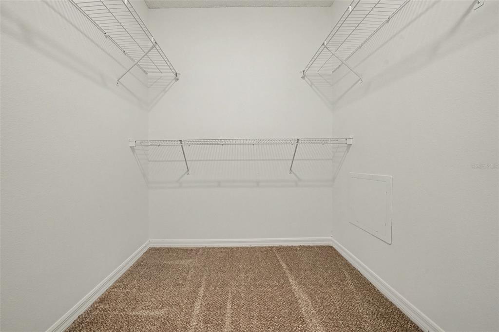 A walk-in closet features white walls, beige carpeting, and white wire shelving — 1099 WELCH HILL CIRCLE, APOPKA, FL