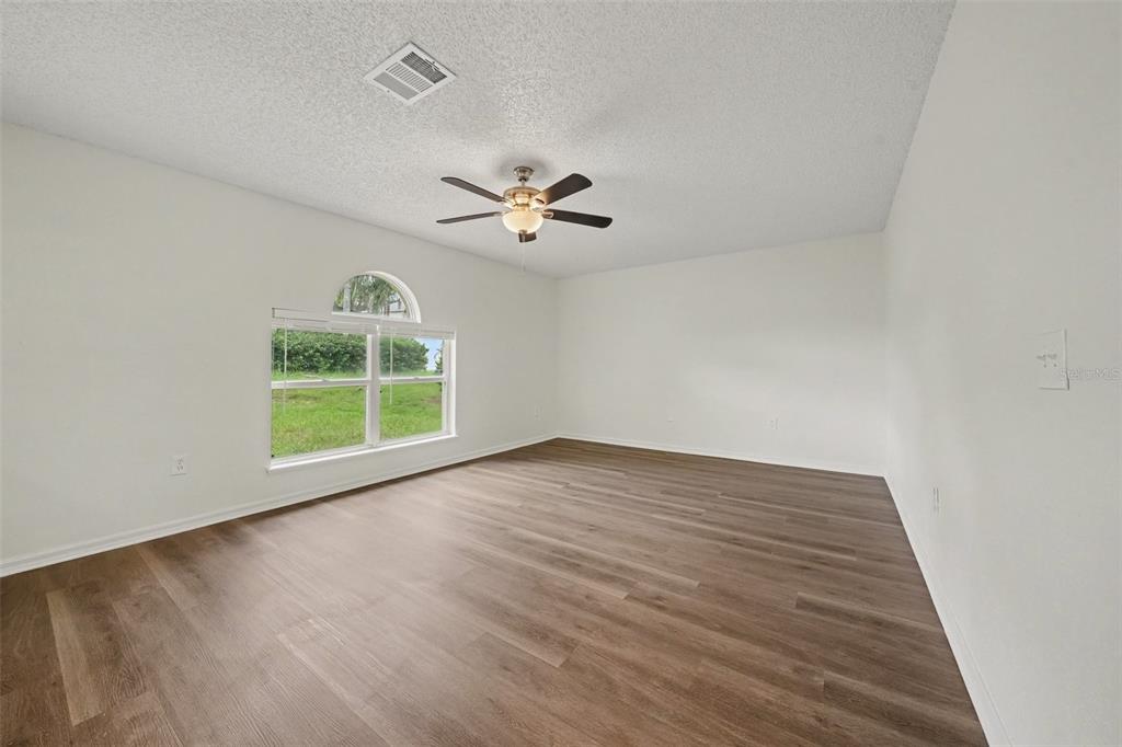 An empty room with white walls, wood-look flooring, a ceiling fan, and an arched window — 1099 WELCH HILL CIRCLE, APOPKA, FL