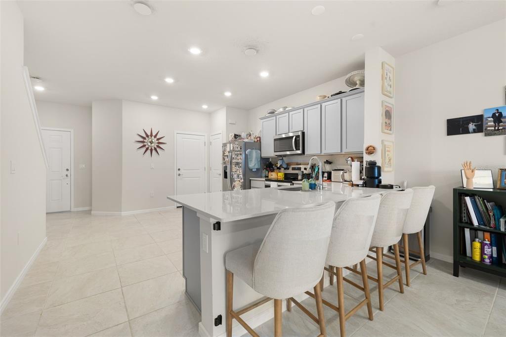 A kitchen features a large island with bar seating, light gray cabinets, and tile flooring — 2615 WINSOME WAY, DAVENPORT, FL