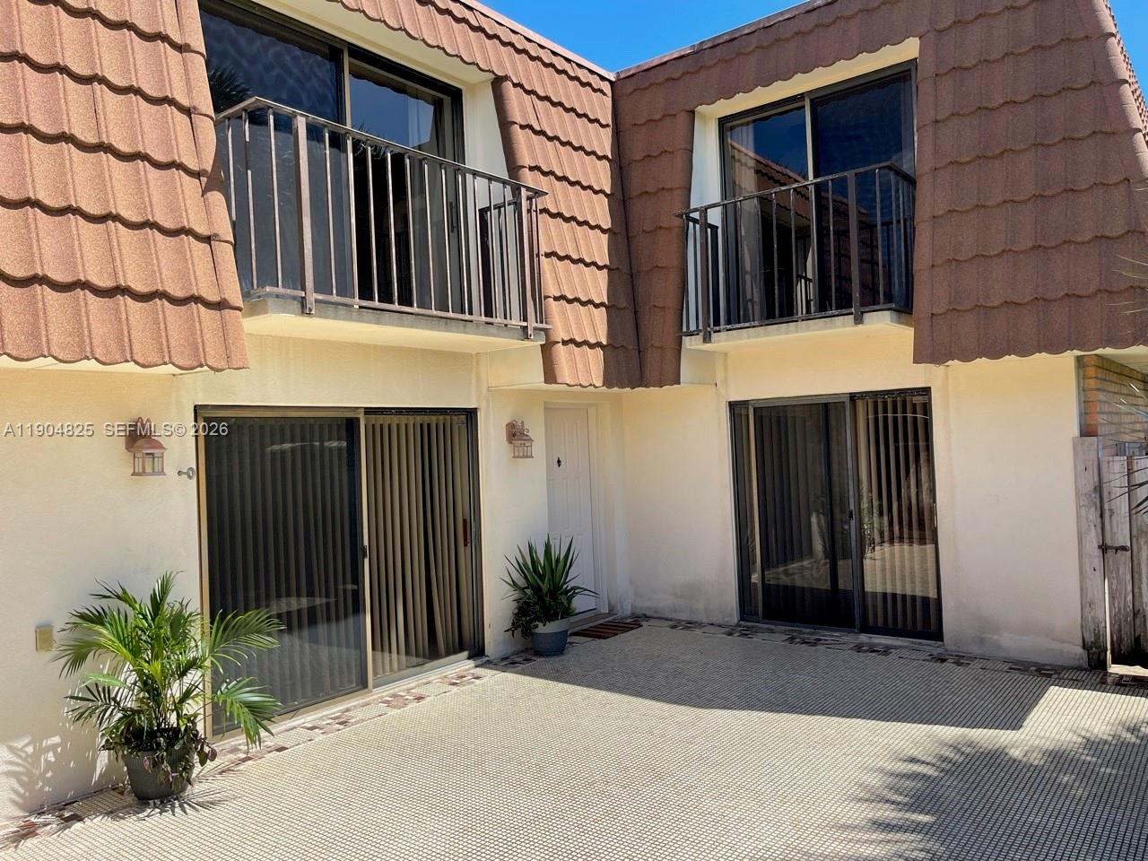 A two-story building exterior features a tiled mansard roof, balconies, and a paved patio area — 157 Heritage Way, West Palm Beach FL 33407, WEST PALM BEACH, FL
