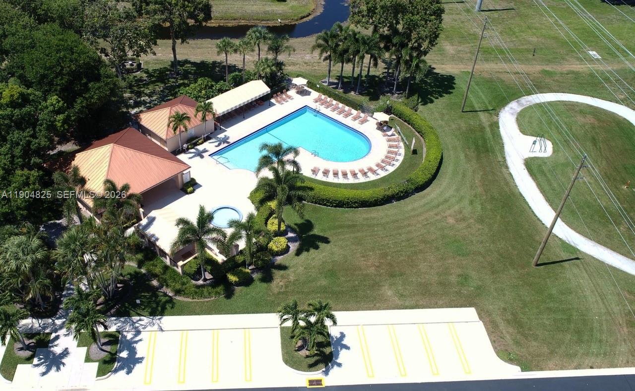 An aerial view shows a swimming pool with a deck, lounge chairs, and adjacent buildings — 157 Heritage Way, West Palm Beach FL 33407, WEST PALM BEACH, FL
