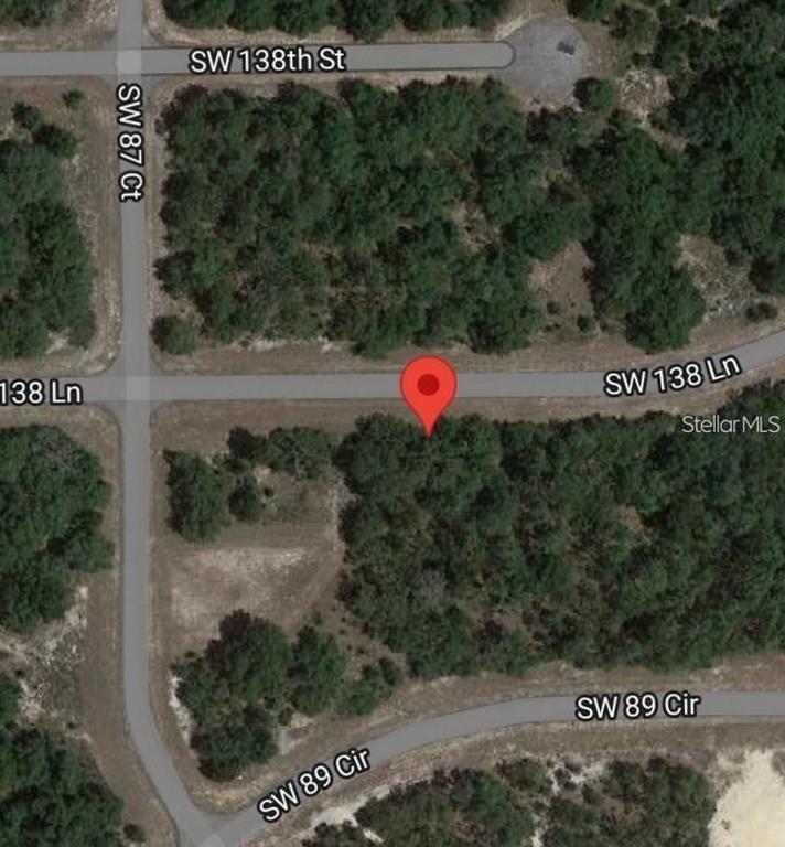 This is a satellite map view showing a vacant wooded lot with a red location pin — 8650 SW 138 LANE, OCALA, FL