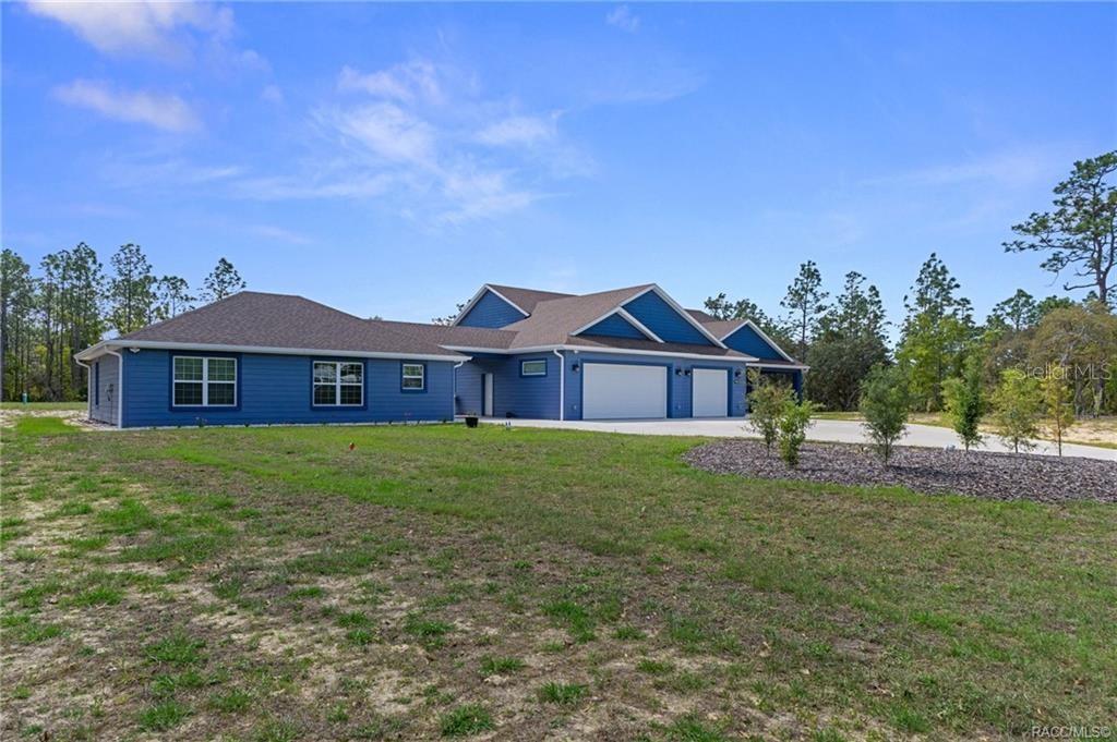 A blue house with a multi-car garage sits on a large, grassy lot — 4999 N TEE PEE DRIVE, BEVERLY HILLS, FL
