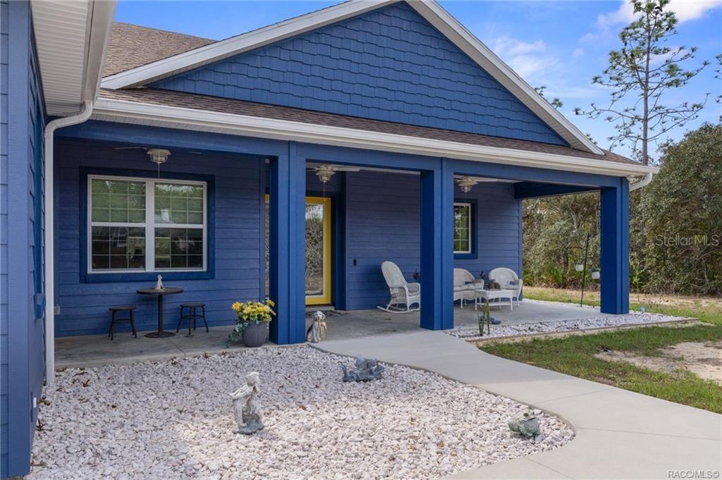 A blue house with a covered front porch, white rock landscaping, and a concrete walkway — 4999 N TEE PEE DRIVE, BEVERLY HILLS, FL