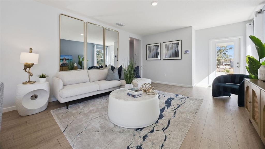 A living room features a white sofa, a round coffee table, and three large wall mirrors — 1856 HOWARD MESA DRIVE, KISSIMMEE, FL