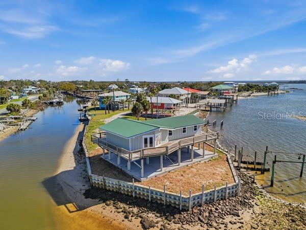 An elevated house with a green metal roof sits on a point overlooking the water — 18 4TH STREET, HORSESHOE BEACH, FL