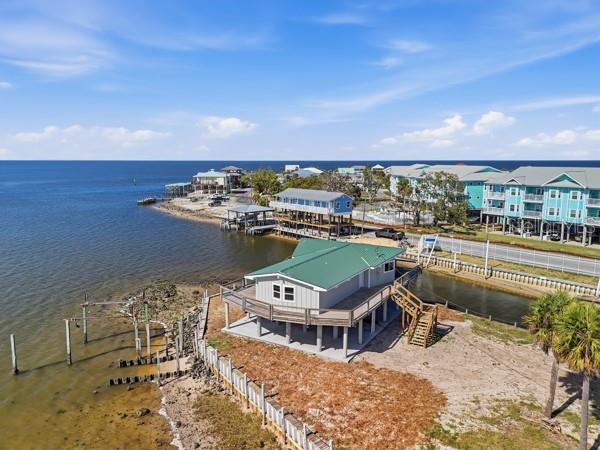 An elevated coastal house with a green metal roof sits near a body of water — 18 4TH STREET, HORSESHOE BEACH, FL