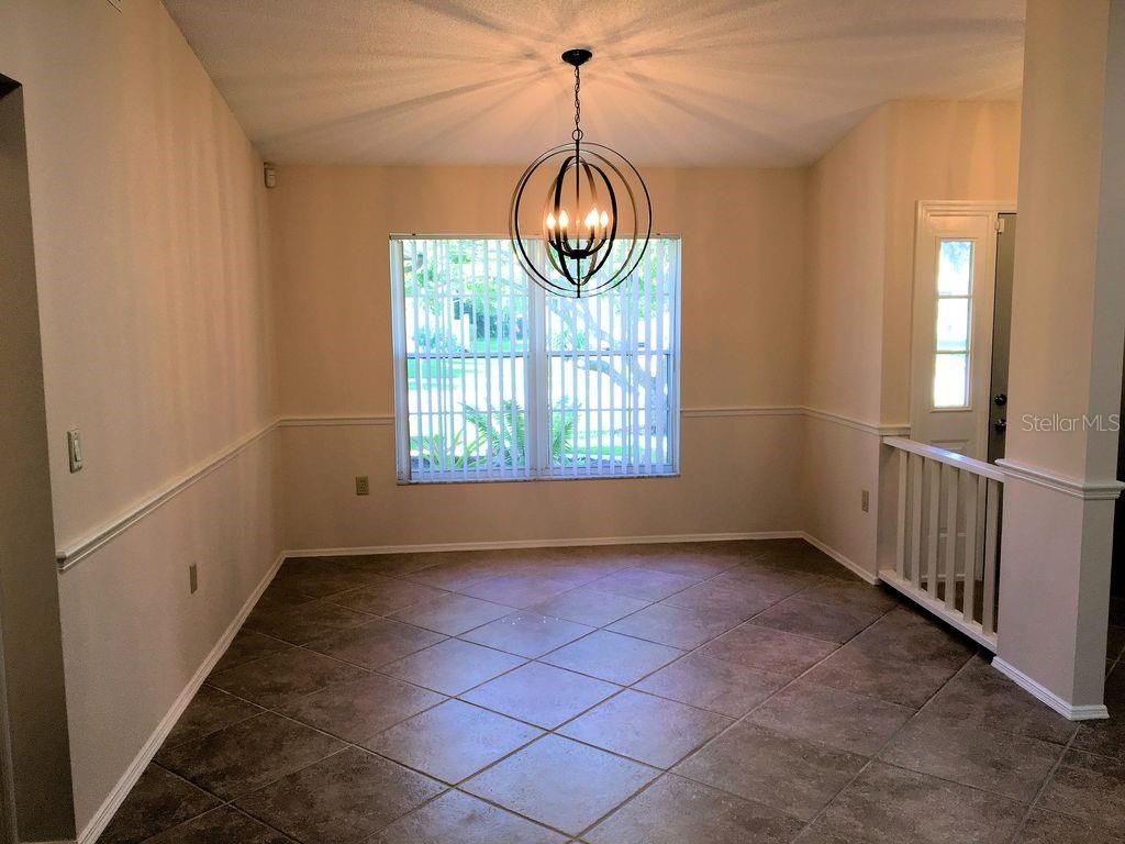 A dining area with tile flooring, a large spherical chandelier, and a window with blinds — 2278 CORK OAK STREET W, SARASOTA, FL