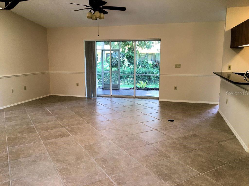 An open-concept living area features light-colored tile flooring and sliding glass doors to a patio — 2278 CORK OAK STREET W, SARASOTA, FL