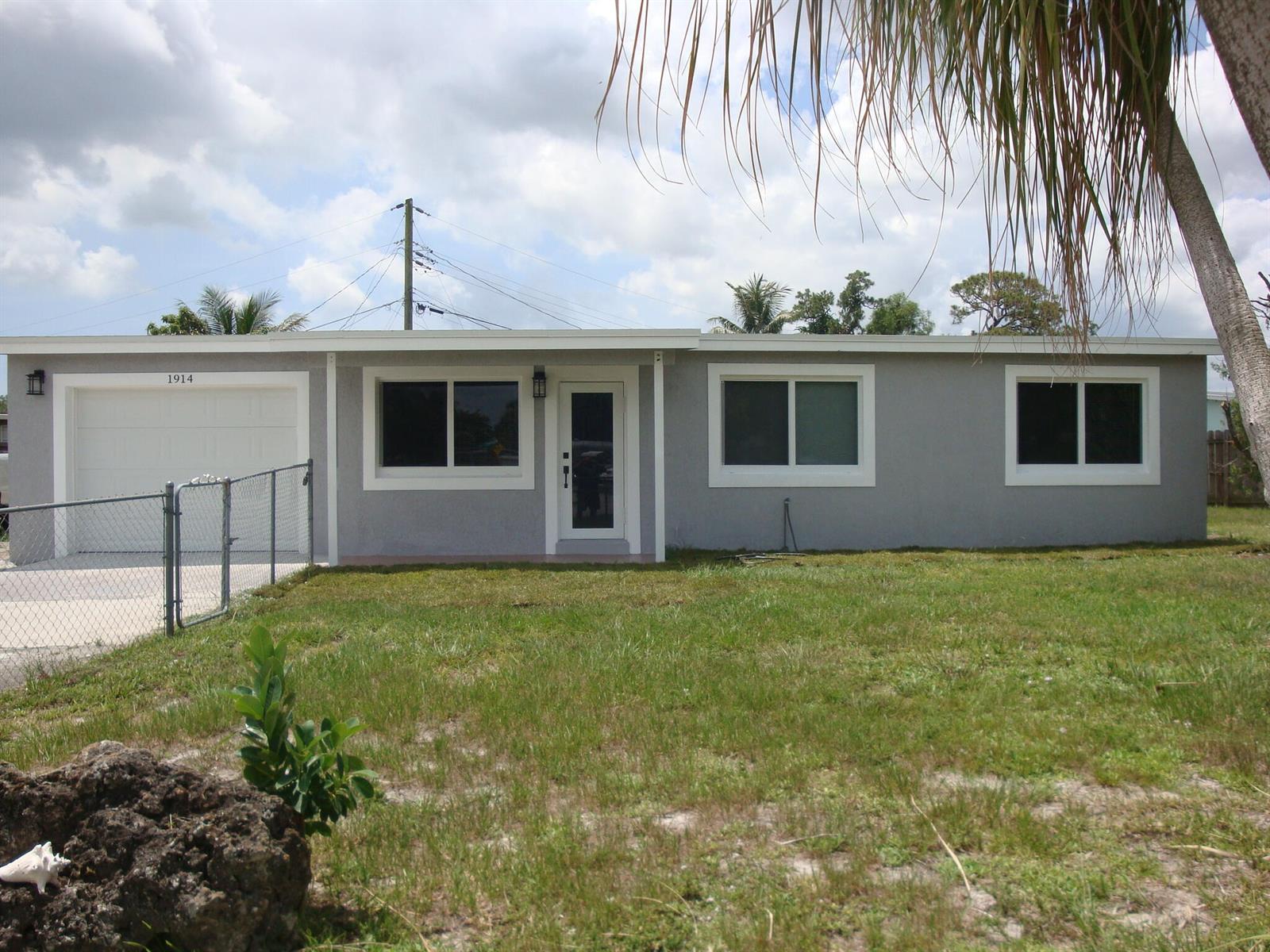 A single-story gray house with a white garage door and a front entrance — 1914 Kudza Road, West Palm Beach FL 33415, WEST PALM BEACH, FL