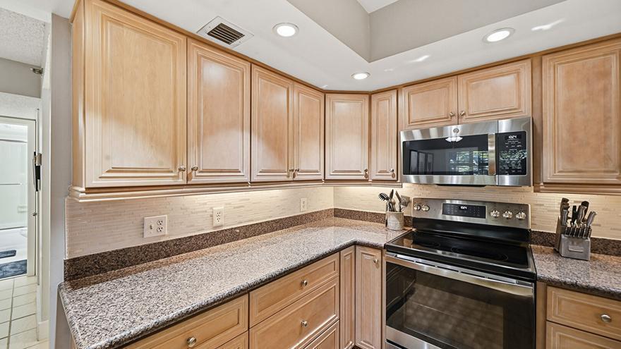 A kitchen features light wood cabinets, granite countertops, stainless steel appliances, and a tiled backsplash — 500 Ocean Trail Way # 207, Jupiter FL 33477, JUPITER, FL