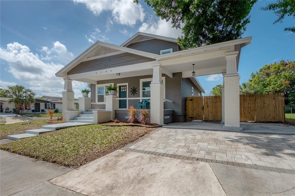 A gray bungalow with a front porch, a paved driveway, and a wooden fence — 2702 W PALMETTO STREET, TAMPA, FL