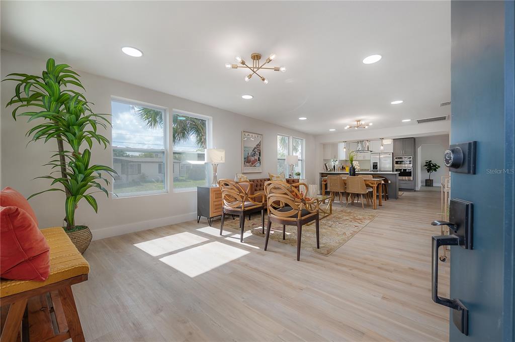 An open-concept living and dining area features light wood flooring, recessed lighting, and modern furniture — 2702 W PALMETTO STREET, TAMPA, FL