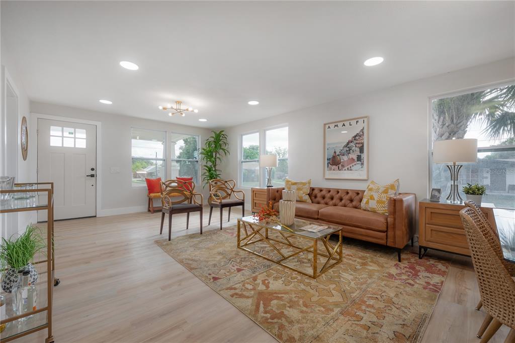 A living room features light wood flooring, a leather sofa, and a patterned area rug — 2702 W PALMETTO STREET, TAMPA, FL