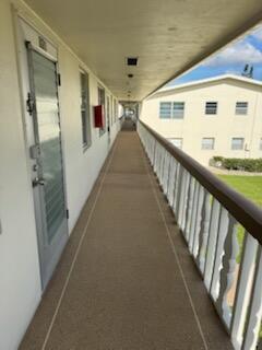 An exterior walkway with a beige floor, white railing, and a door leading to a unit — 321 Northampton, West Palm Beach FL 33417, WEST PALM BEACH, FL
