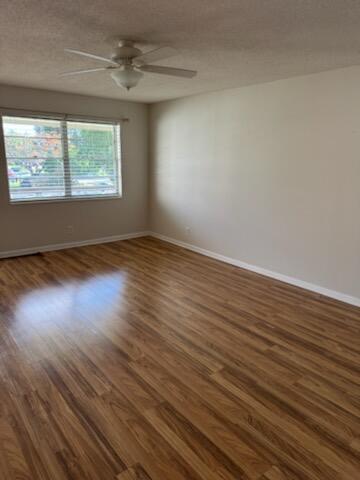 An empty room with wood-look flooring, a ceiling fan, and a window overlooking a street — 321 Northampton, West Palm Beach FL 33417, WEST PALM BEACH, FL