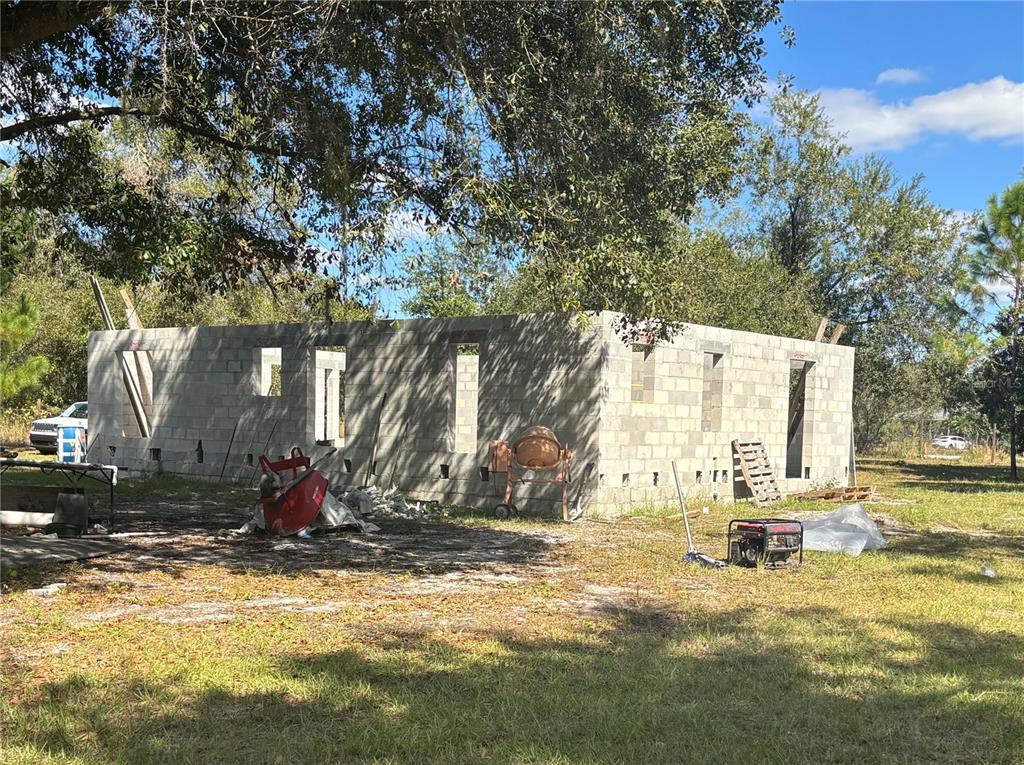 A partially constructed concrete block building stands on a grassy lot with construction equipment nearby — 432 WILDLIFE TRAIL, LAKELAND, FL