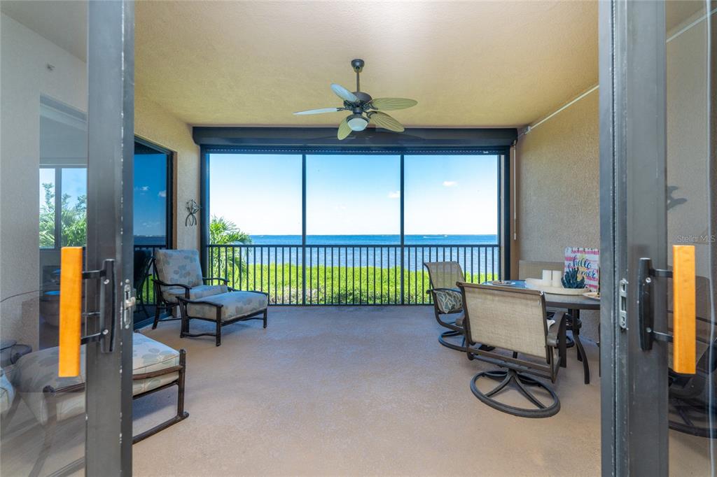 A screened-in balcony features a ceiling fan, outdoor furniture, and a view of the water — 85 VIVANTE BOULEVARD UNIT 8524, PUNTA GORDA, FL