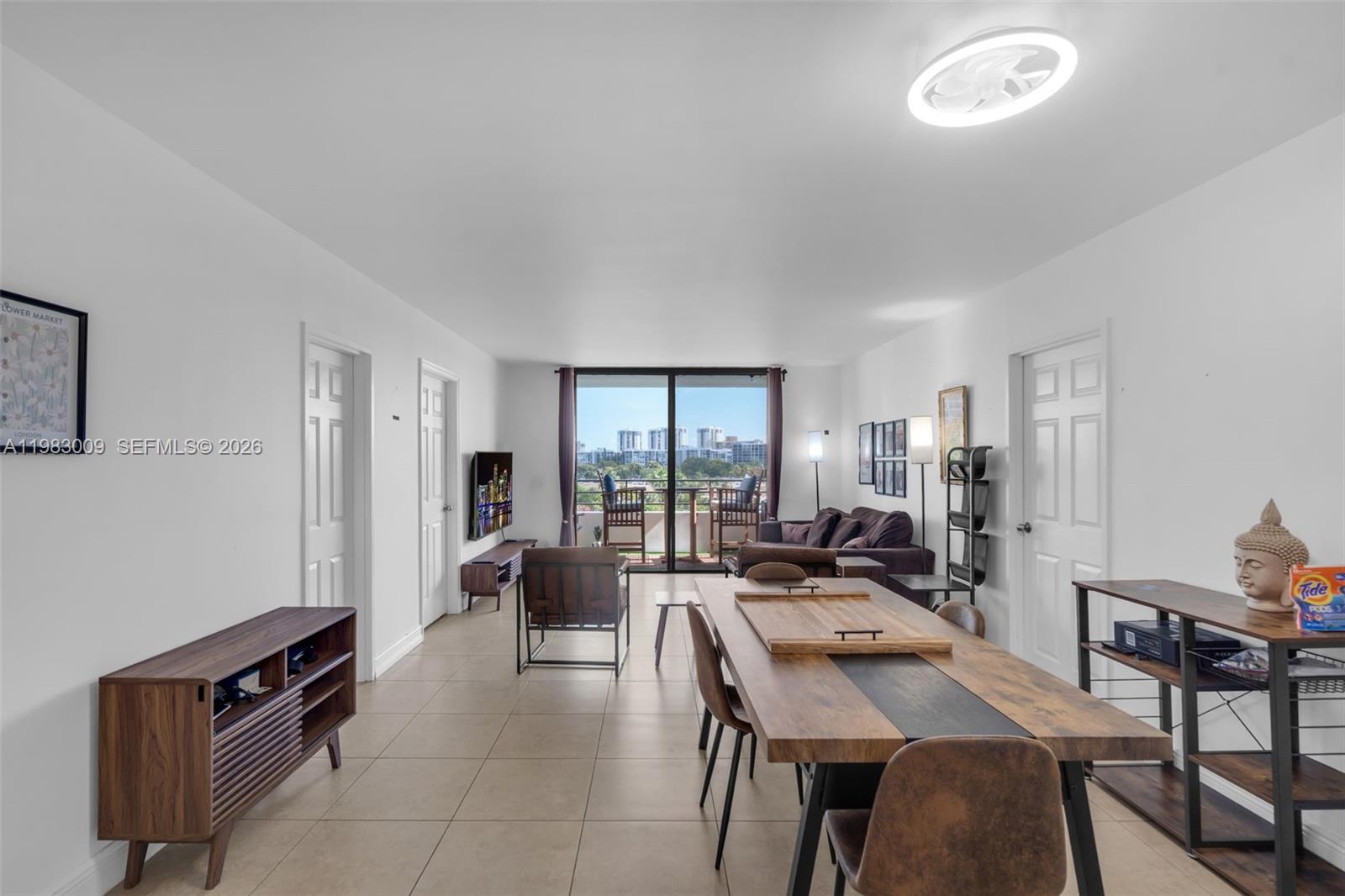 A living and dining area with tile floors, a balcony, and modern wooden furniture — 500 Three Islands Blvd # 226, Hallandale Beach FL 33009, HALLANDALE BEACH, FL