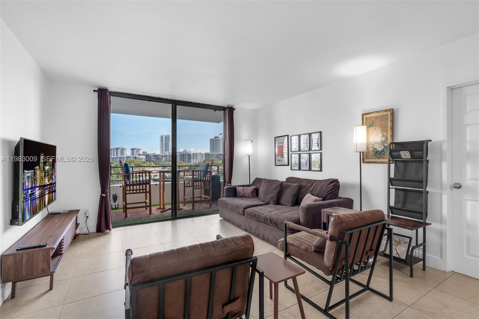 A living room features tile flooring, a brown sofa, two armchairs, and a balcony view — 500 Three Islands Blvd # 226, Hallandale Beach FL 33009, HALLANDALE BEACH, FL