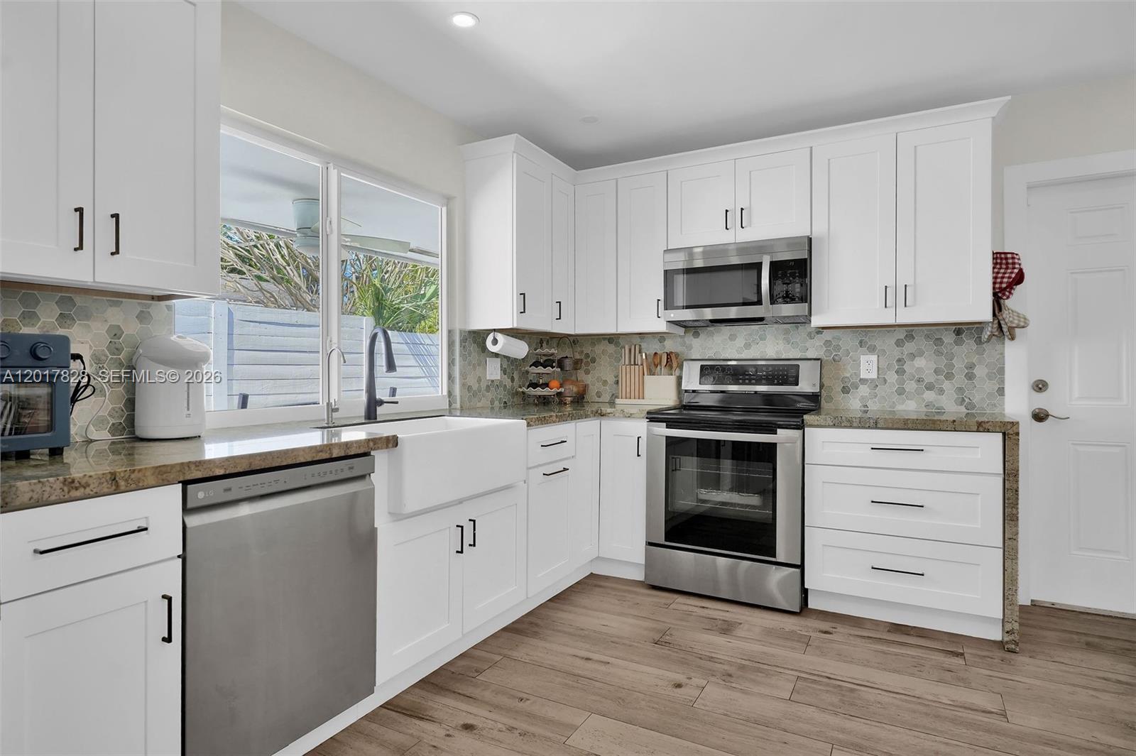 A kitchen features white cabinets, stainless steel appliances, a farmhouse sink, and hexagonal tile backsplash — 1301 Hollywood Blvd, Hollywood FL 33019, HOLLYWOOD, FL